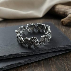 Woman wearing antique silver elephant link bracelet on her wrist against a dark background