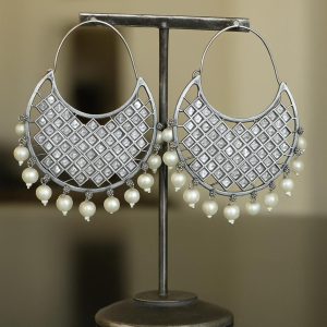 Oxidized silver geometric hoop earrings with square white stones and hanging pearl beads on a jewelry stand