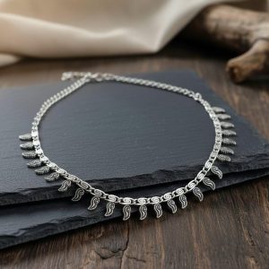 Close up view of antique silver ethnic necklace featuring textured mango or leaf motifs on a link chain
