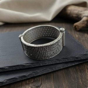 Wide antique silver hinged bangle with geometric dot texture on slate background