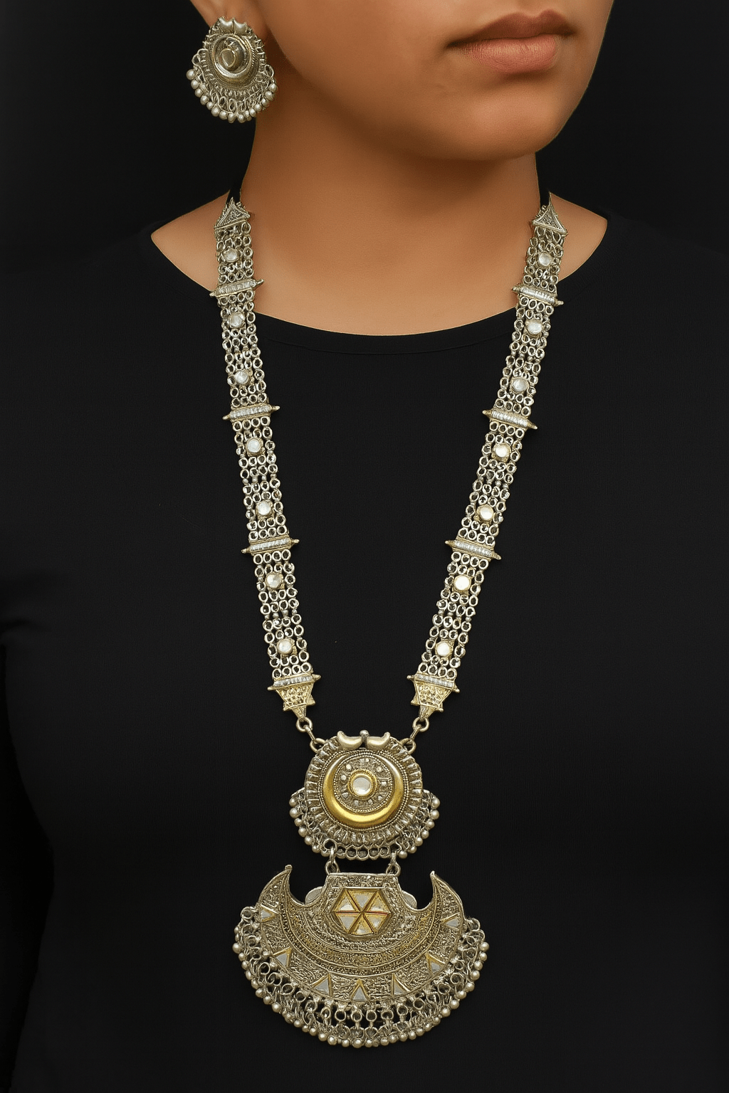 Flat lay of dual tone oxidized silver and gold necklace set on white background.