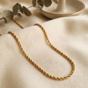 Gold twisted rope chain necklace displayed on a white jewelry mannequin bust against a plain background