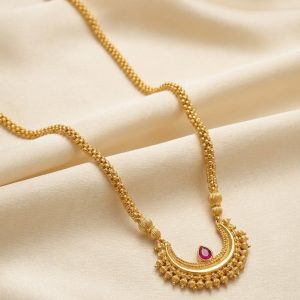Close-up detail of gold U-shaped pendant with red ruby and rava granulation work