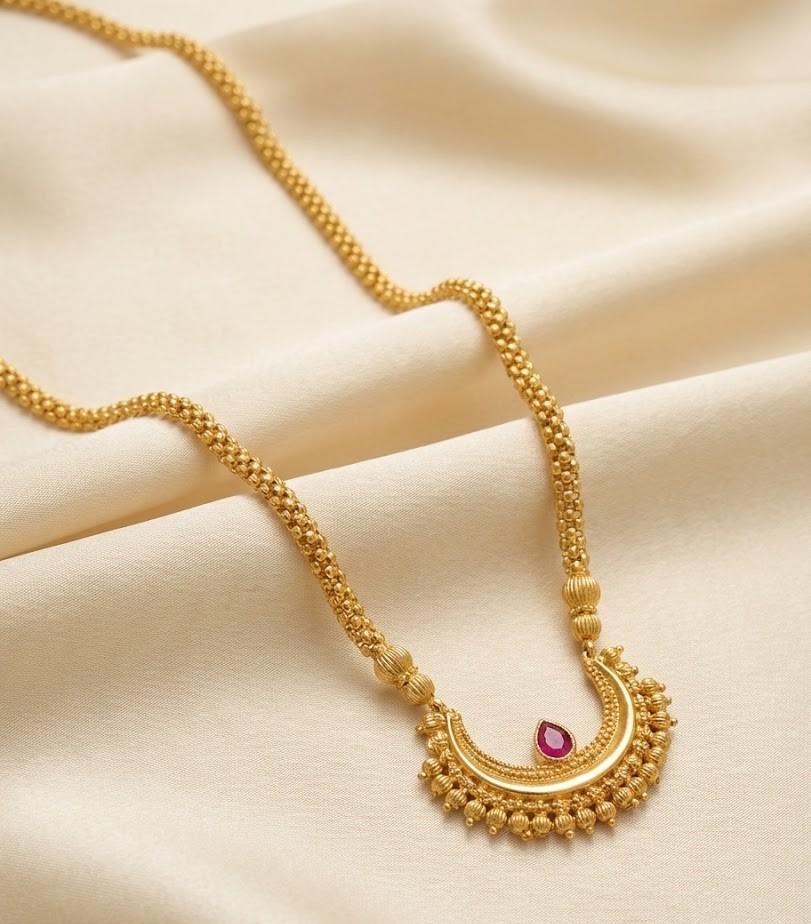 Close-up detail of gold U-shaped pendant with red ruby and rava granulation work