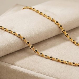 Flat lay of gold plated long necklace with black beads on texture background.